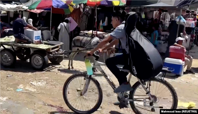 In this frame captured from video, Palestinian teenager Youssef Saad rides his bicycle with his musical instrument strapped to his back amid Israel-Hamas conflict, in Jabalia refugee camp in the northern Gaza Strip September 2, 2024. (REUTERS/Mahmoud Issa)