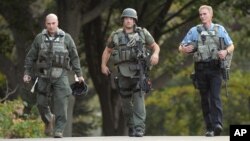 FILE - Minneapolis police officers walk to Accent Signage Systems as police investigate a shooting at a business in the Bryn Mawr neighborhood of Minneapolis, Sept. 27, 2012.