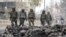 Security forces patrol past charred vehicles in a riot affected area following clashes between people demonstrating for and against a new citizenship law in New Delhi, Feb. 27, 2020.