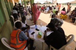 FILE - Health workers attend to people during a community COVID-19 coronavirus testing campaign in Abuja, Nigeria, on April 15, 2020.