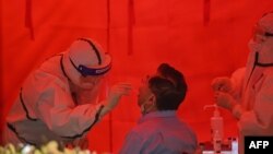A medical worker takes a swab sample from a man to test for the COVID-19 coronavirus in Wuhan, in China’s central Hubei province on May 19, 2020.