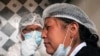 Una trabajadora de la salud le administra un hisopo nasal a una vendedora en un punto de prueba de para detectar COVID-19, en el mercado de Sopocachi en La Paz, Bolivia, el 26 de diciembre de 2020.