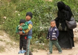 FILE - Woman and children of Islamic state militants walk as they surrendered in the village of Baghouz, Deir Al Zor province, Syria, March 14, 2019.