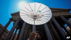 Un hombre se protege del sol con una sombrilla de papel frente al Panteón de Roma durante una ola de calor, el jueves 11 de julio de 2024. 