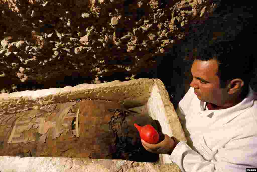 A Egyptian archaeologist is seen next to a coffin inside a tomb during the presentation of a new discovery at Tuna el-Gebel archaeological site in Minya Governorate, Egypt, Feb. 2, 2019.