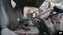 Police and residents stand near a vehicle, which was transporting police officials, after it was hit by a bomb in Peshawar, Pakistan. Aug. 11, 2011.