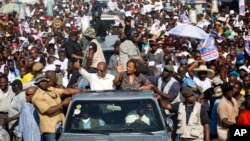 FILE -- Haiti's former President Jean-Bertrand Aristide, left, waves to supporters as he campaigns with presidential candidate Maryse Narcisse of the Fanmi Lavalas political party in Port-au-Prince, Haiti, in mid-September. Haiti will hold elections Oct. 9.
