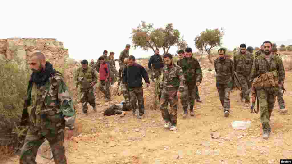 Forces loyal to Syria's President Bashar al-Assad carry their weapons and walk in Aleppo's village of Aziza, Nov. 25, 2013.