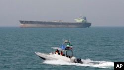 FILE - An Iranian Revolutionary Guard speedboat moves in the Persian Gulf while an oil tanker is seen in background, July 2, 2012. The United Arab Emirates said Wednesday that nine people held by Iran since January after being detained in the Persian Gulf have been freed. 