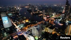 FILE - Cars and trains move on Taksin bridge over Chao Phraya river in central Bangkok, at sunset, March 14, 2013. 