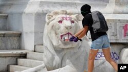 A woman hits a statue of a lion with a sledgehammer as protestors angry at the police attack the monument to Mexico's first indigenous president, Benito Juárez, during an anti-police protest in Mexico City, June 8, 2020.