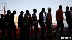 Les migrants interceptés à bord d'un canot au large de la côte méditerranéenne, quittent un bateau de sauvetage à leur arrivée au port de Malaga, dans le sud de l'Espagne, le 7 juillet 2018.