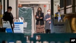 Former first lady and former US Secretary of State Hillary Clinton, center right, closes her coat as she leaves the University of California Irvine Medical Center before midnight in Orange, Calif., Oct. 14, 2021. 