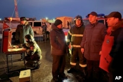 In this photo released by Russian officials on Jan. 8, 2025, the governor of Russia's Saratov region, Roman Busargin, second right, speaks to firefighters and rescuers at the industrial site damaged in a Ukrainian drone attack. (Saratov region governor's Telegram channel via AP)