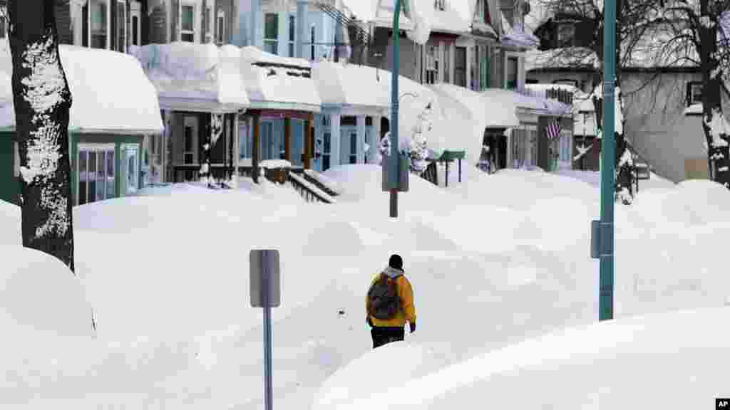 Brian Cintron marche dans son quartier de Buffalo sud couvert de neige, jeudi 20 novembre 2014, à Buffalo, NY. Une tempête de neige s&rsquo;est abattue sur Buffalo pour la troisième journée consécutive causant plus de misère à une ville déjà enterrée par une tombée de neige meurtrière qui pourrait laisser quelques zones avec près de 2,5 mètres de neige.