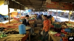 Penjual sayur India mengobrol ketika mereka menunggu pelanggan selama masa karantina wilayah untuk mengontrol penyebaran virus corona di pinggiran New Delhi, India, Selasa, 7 April 2020. (Foto: AP)