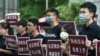 FILE - Hong Kong students and Taiwanese supporters hold signs protesting Beijing's national security legislation in Taipei, Taiwan, May 28, 2020.
