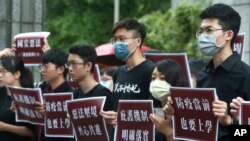 Hong Kong students and Taiwanese supporters hold slogans reading: "Evil law under the pressure of the border, Work hand in hand " and ''The asylum mechanism is clearly in place'' during a protest against Beijing's national security legislation 