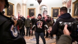 Trumpov pristaša Douglas Austen Jensen, odjeven u majicu QAnona, suočava se s policijom na drugom katu američkog Kapitola u Washingtonu, 6. siječnja 2021. godine.