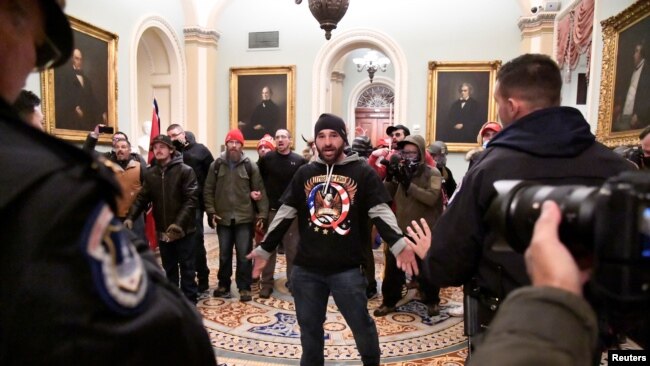 Trump supporter Douglas Austen Jensen, wearing a QAnon shirt, confronts police on the second floor of the U.S. Capitol after breaching security defenses, in Washington, January 6, 2021.
