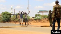 Civilians approach security officers to be questioned at a roadblock near the site where gunmen abducted two Cuban doctors as they were on their way to work, in Mandera county, Kenya, April 12, 2019.