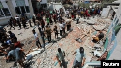 Palestinians inspect a school sheltering displaced people following an Israeli strike in Deir al Balah in the central Gaza Strip on July 27, 2024.