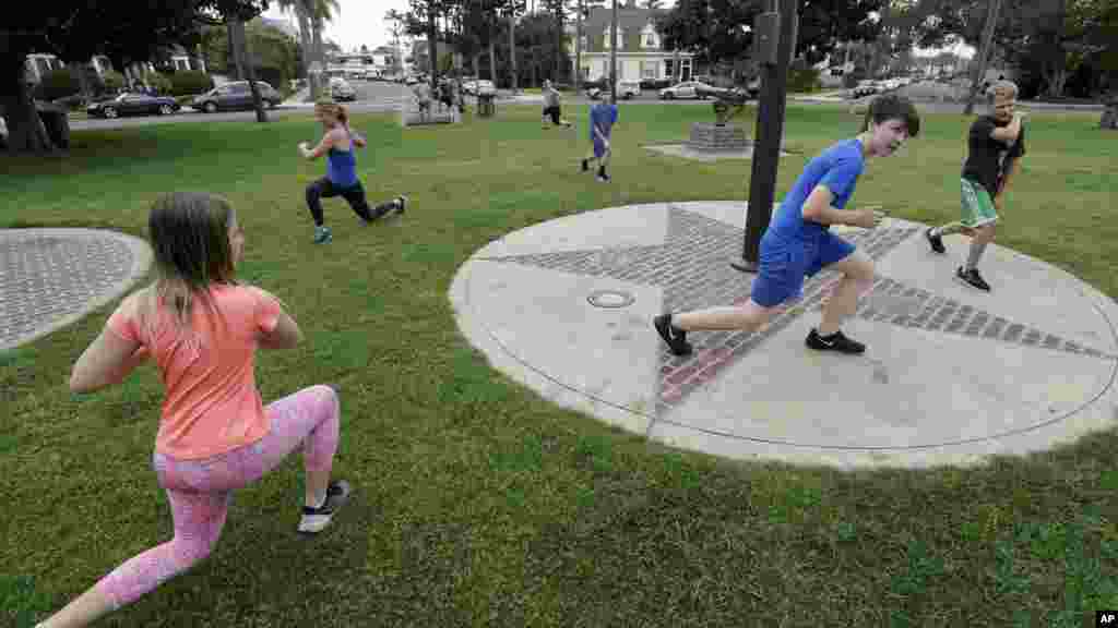 Varios niños se ejercitan junto a sus padres en un parque en Coronado, California. Un gimnasio local trasladó su clase al aire libre para que los niños puedan unirse y ejercitarse debido a las restricciones impuestas por las autoridades sanitarias en cuanto al uso de espacios cerrados para grupos numerosos de personas.