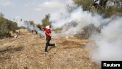 A Palestinian protester returns a tear gas canister fired by Israeli troops during clashes over tension in Jerusalem's al-Aqsa mosque, in the occupied West Bank village of Budrus near Ramallah, October 2, 2015.