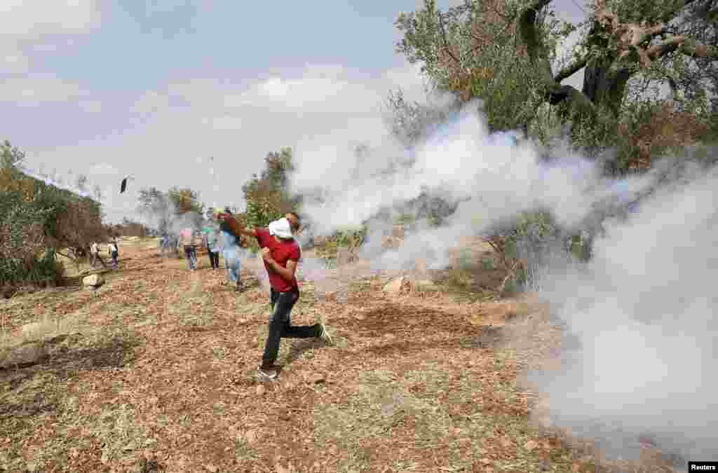 Seorang demonstran Palestina melemparkan kembali kaleng gas air mata yang ditembakkan oleh tentara Israel dalam bentrokan mengenai ketegangan di masjid al-Aqsa di Yerusalem, di desa Budrus dekat Ramallah, Tepi Barat (2/10). ​(Reuters/Mohamad Torokman)