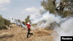 Seorang demonstran Palestina melemparkan kembali gas air mata yang ditembakkan oleh tentara Israel dalam bentrokan akibat ketegangan di Masjid al-Aqsa, Yerusalem, di desa Budrus dekat Ramallah, 2 Oktober 2015.