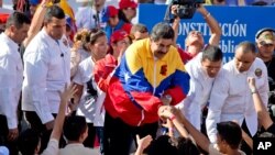 រូបភាព​ឯកសារ៖ប្រធានាធិបតី​វ៉េណេស៊ុយអេឡា Nicolas Maduro (កណ្តាល) ព័ទ្ធ​ដោយ​ក្រុម​កង​អង្គរក្ស ចាប់​ដៃ​ជាមួយ​អ្នក​គាំ​ទ្រ​នៅ​ក្នុង​ការ​ដើរ​ប្រឆាំង​អាមេរិក​នៅ​ក្នុង​ទីក្រុង Carcacas ប្រទេស​វ៉េណេស៊ុយអេឡា កាល​ពី​ថ្ងៃ​ច័ន្ទ​ ទី​១៥ ខែ​ធ្នូ ឆ្នាំ​២០១៤។