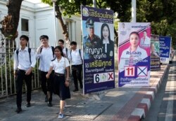 Students of Chulalongkorn University walks past election campaign posters in Bangkok, Thailand, March 12, 201.