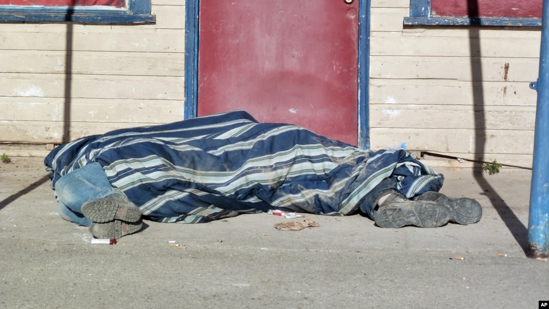 In this Aug. 9, 2013, photo homeless people cover themselves with a blanket on a street in Whiteclay, Neb. Many tribal members live on the tiny town's barren streets to avoid arrest on the nearby reservation for being intoxicated. 