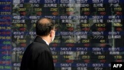 A pedestrian looks at an electronic quotation board displaying companies' stock prices on the Tokyo Stock Exchange in Tokyo on Jan. 7, 2021. 