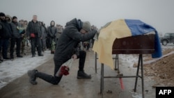 A man mourns next to the coffin containing the body of Anton Spitsyn, a Ukrainian serviceman killed fighting Russian troops, during a funeral ceremony in Kharkiv, Ukraine, on Feb. 5, 2025.