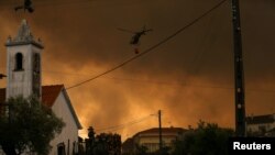 Helikopter pemadam kebakaran terbang melintasi wilayah Leiria, Portugal, untuk mengatasi kebakaran di wilayah tersebut pada 13 Juli 2022. (Foto: Reuters/Rodrigo Antunes)