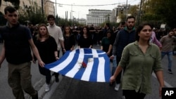 University students hold a blood-stained Greek flag from the deadly 1973 student uprising during a rally in Athens, Nov. 17, 2019. 