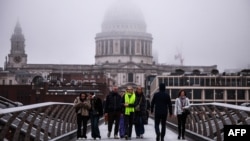 Pedestrians cross The Millennium Bridge with the dome of St Paul's Cathedral disappearing into the fog behind, in London on Dec. 27, 2024.