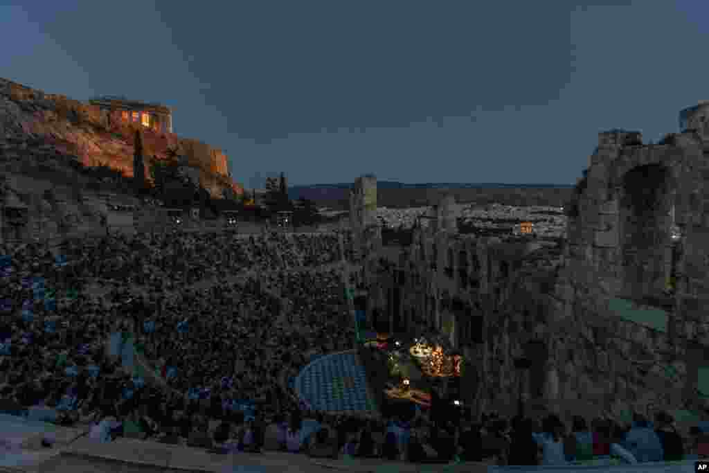 Actors and singers perform at the Odeon of Herodes Atticus in Athens, Greece, after the site was reopened for performances, July 15, 2020, with the ancient Parthenon temple in the background.