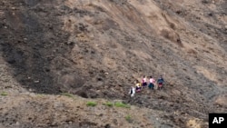 Residents walk in an area swept by a landslide in Alausi, Ecuador, March 28, 2023, the day after the avalanche buried dozens of homes.