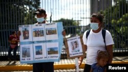 Manifestantes muestran retratos de familiares detenidos bajo el estado de excepción durante una protesta frente al Congreso de El Salvador el 16 de agosto de 2022. Foto AP.