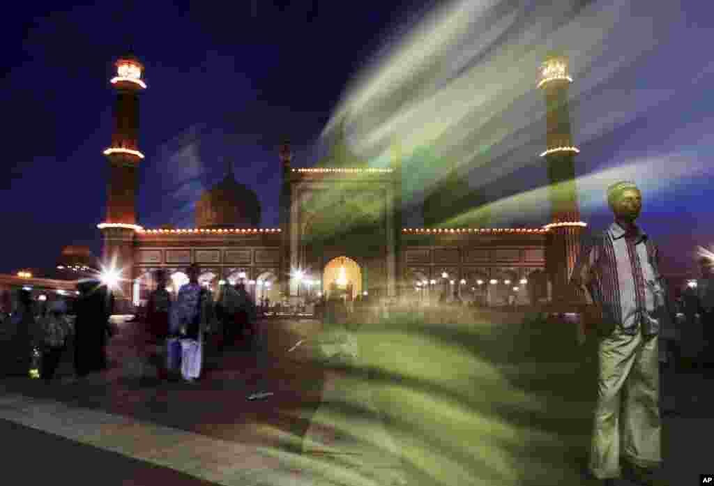 An Indian Muslim man stands in front of the Jama Masjid as he and other worshippers leave following the breaking of the fast and prayers on the first night of Ramadan in New Delhi, India.