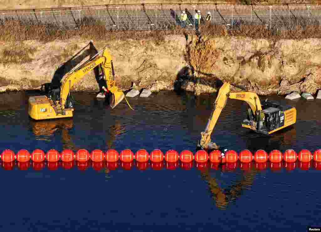 A drone view shows workers assembling a string of buoys to deter migrants from crossing the Rio Grande river from Mexico into Eagle Pass, Texas, as seen from Piedras Negras, Mexico, Jan. 21, 2025.