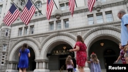 FILE - A group of people approach the front facade of the Trump International Hotel to pose for photos in Washington, July 31, 2019. 