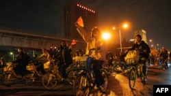 Bicyclists wave flags as thousands of college students clogged highways and streets between the cities of Zhengzhou and Kaifeng in central Henan province, Nov. 9, 2024.