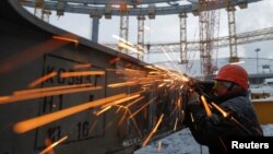 FILE - A laborer works at the Yekaterinburg Arena stadium under construction, that will host 2018 FIFA World Cup matches, in Yekaterinburg, Russia, Dec. 9, 2016. 