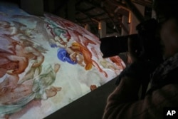 A photographer takes pictures during the preview to the press of the exhibition 'Petros eni', which is part of the project "St. Peter's Basilica: AI-Enhanced Experience" at the Vatican, Saturday, Nov. 9, 2024. (AP Photo/Gregorio Borgia)