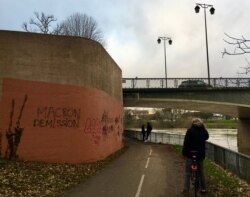 This graffiti in a French suburb calls on President Emmanuel Macron to resign. (Lisa Bryant/VOA)