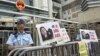 A policeman stands guard next to portraits of Chinese journalist Gao Yu during a demonstration calling for Gao's release from a prison in China, outside the Chinese liaison office in Hong Kong, April 17, 2015.