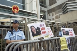 FILE - A policeman stands guard next to portraits of Chinese journalist Gao Yu during a demonstration calling for Gao's release from a prison in China, outside the Chinese liaison office in Hong Kong, April 17, 2015.